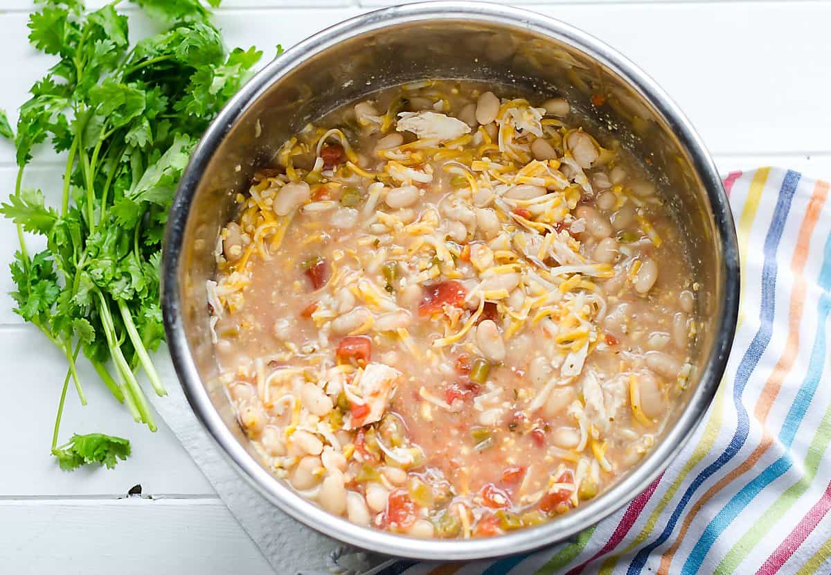 slow cooker/instant pot with white chicken chili ingredients in it before cooked