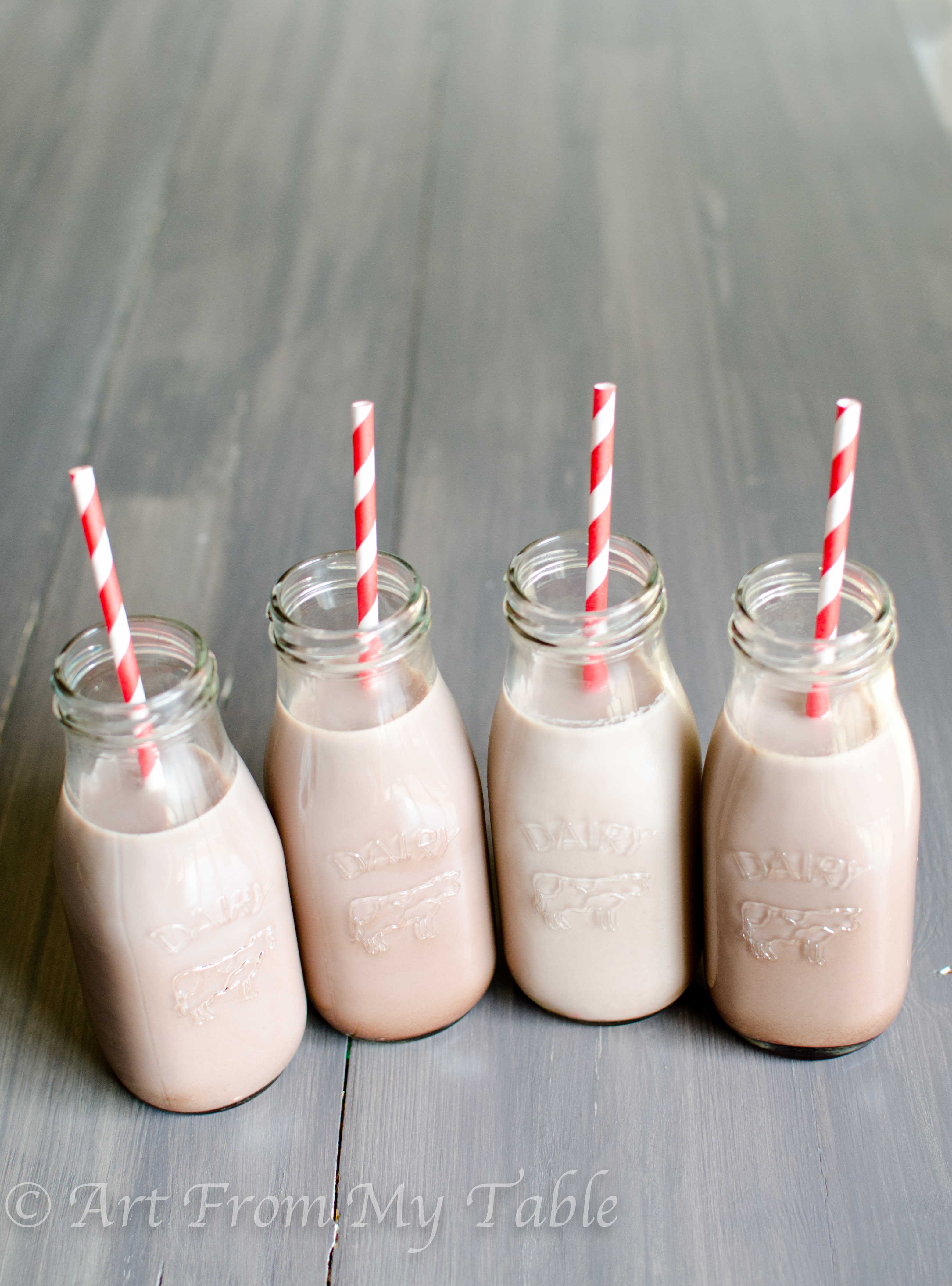 Four small glass milk bottles full of homemade chocolate  milk.