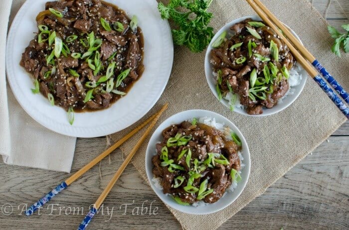 Twp bowls of homemade Mongolian beef on rice with chopsticks.