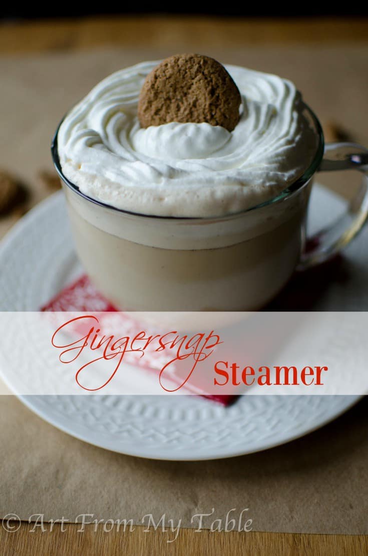 Gingersnap steamer in a glass mug topped with homemade whipped cream and a gingersnap cookie. 