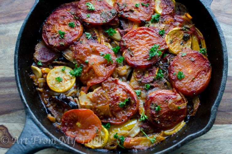 Various vegetables including eggplant, tomatoes, potatoes and squash baked in a cast iron pan with Greek seasonings.