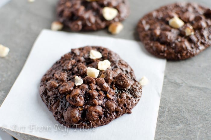 3 chocolate cookies with chopped hazelnuts on top.