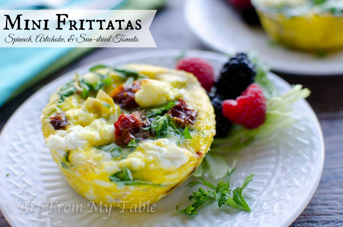 Spinach, artichoke, and sun dried tomato mini frittata on a plate with fresh fruit.