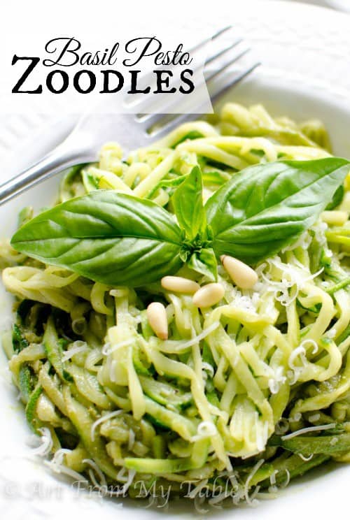 Spiraled zucchini "noodles" mixed with homemade pesto sauce, garnished with pine nuts and a fresh basil leaf.