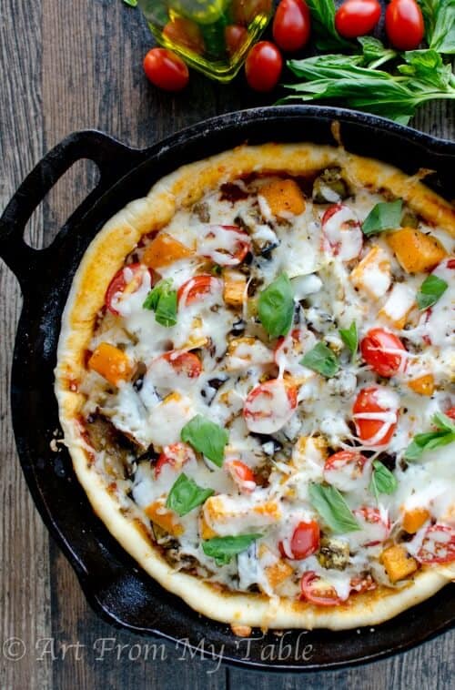 Sausage and roasted veggie pizza in a cast iron pan.