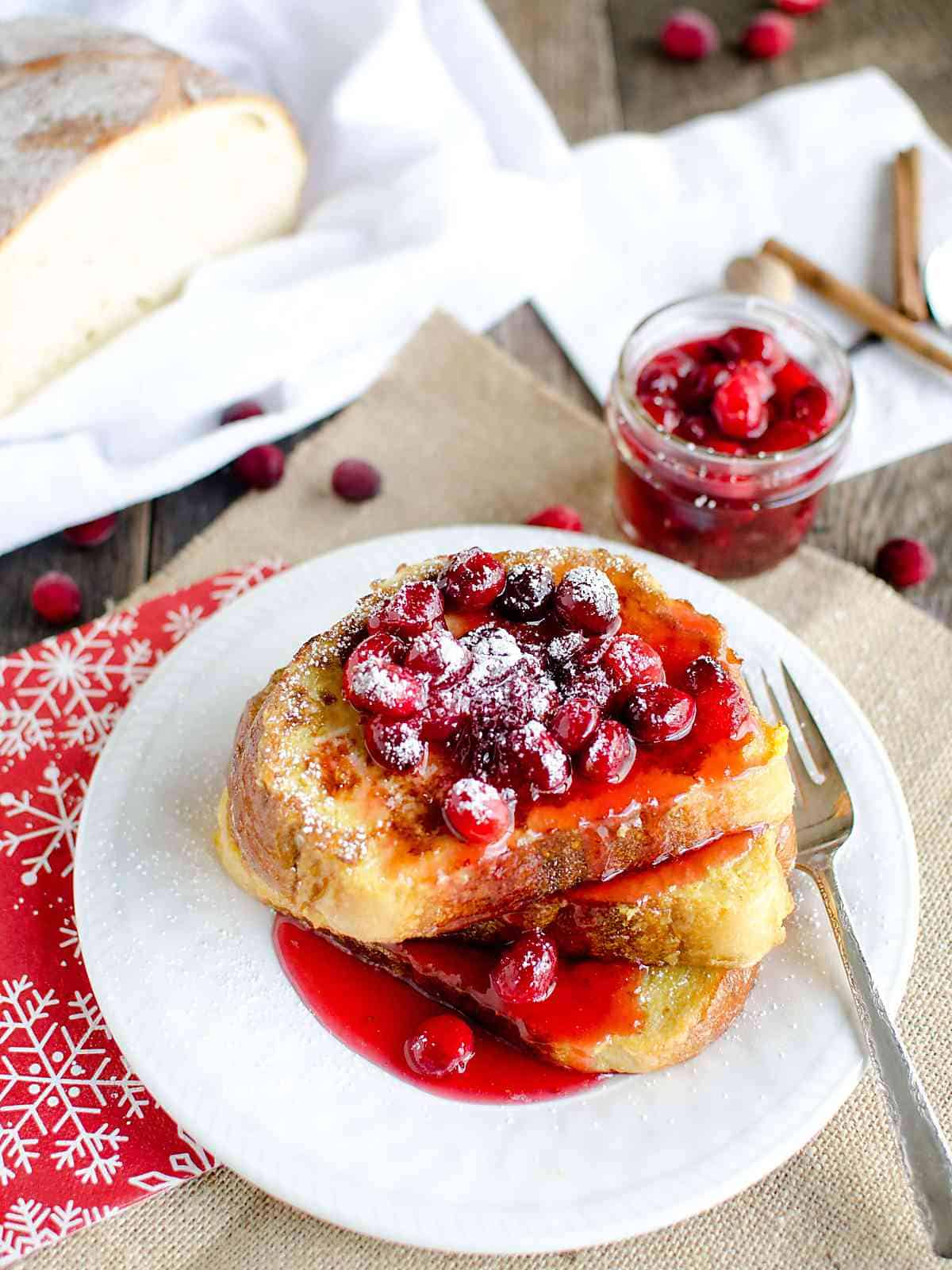 stack of eggnog french toast topped with cranberry syrup and powdered sugar.