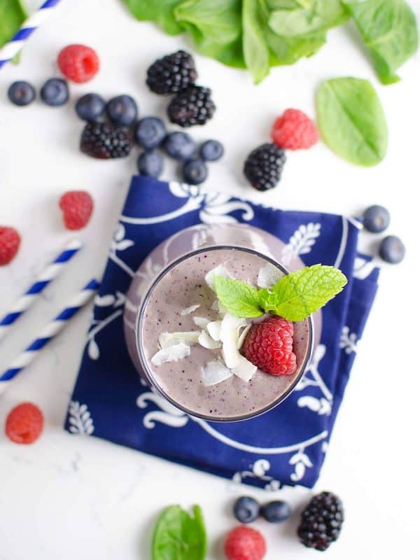 berry blast smoothie on a napkin with berries scattered round it. 