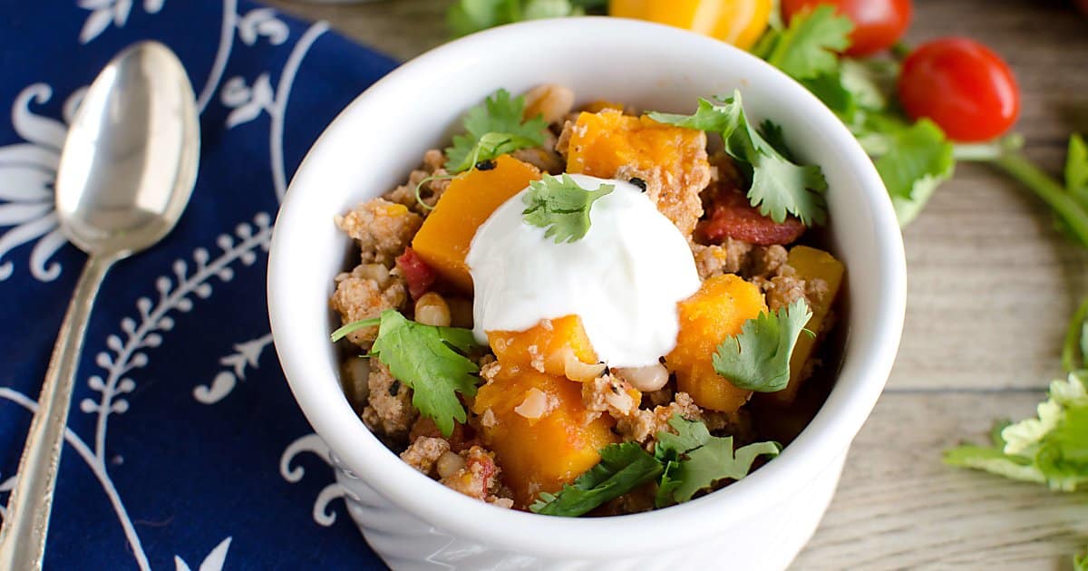 bowl of chili made with ground turkey and butternut squash garnished wtih cilantro and sour cream. 