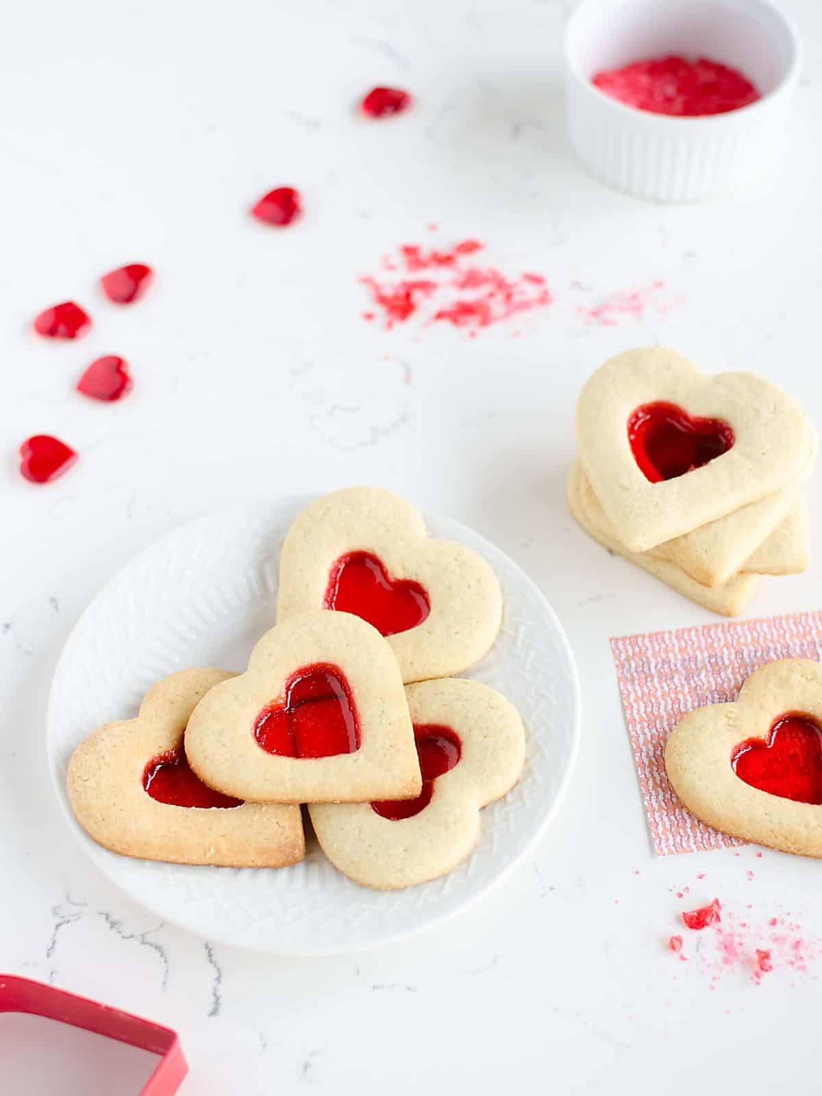 plate of heart shaped Valentines Day sugar cookies that have a red 'stained glass window' in the center
