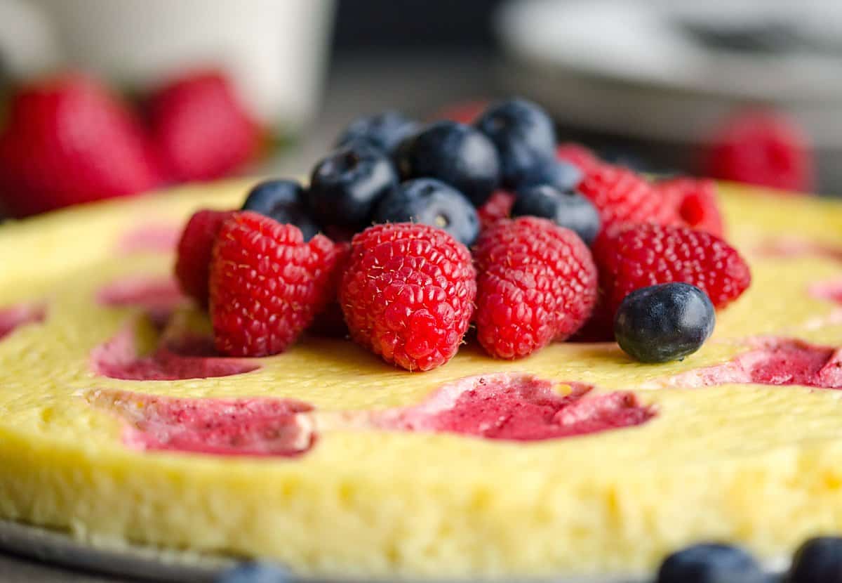 whole cheesecake with strawberry swirl, topped with fresh berries.
