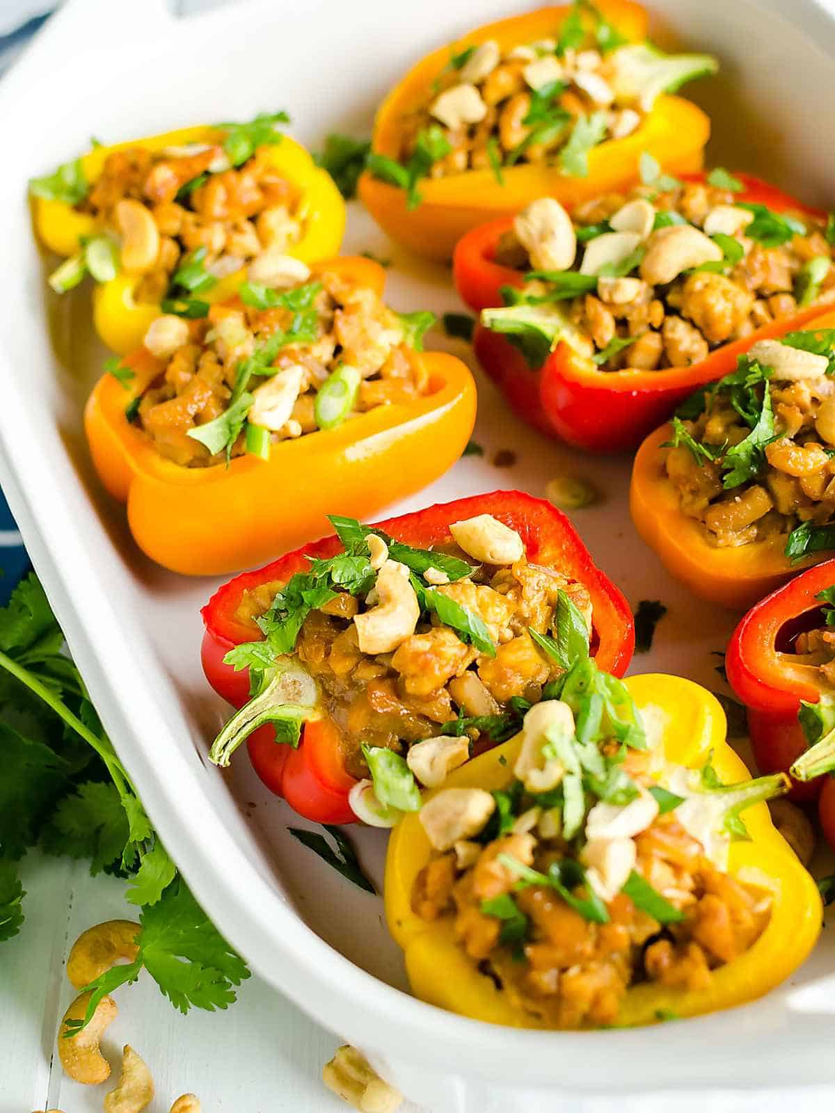 dish of stuffed bell peppers filled with Asian chicken stuffing and topped with peanuts and cilantro.