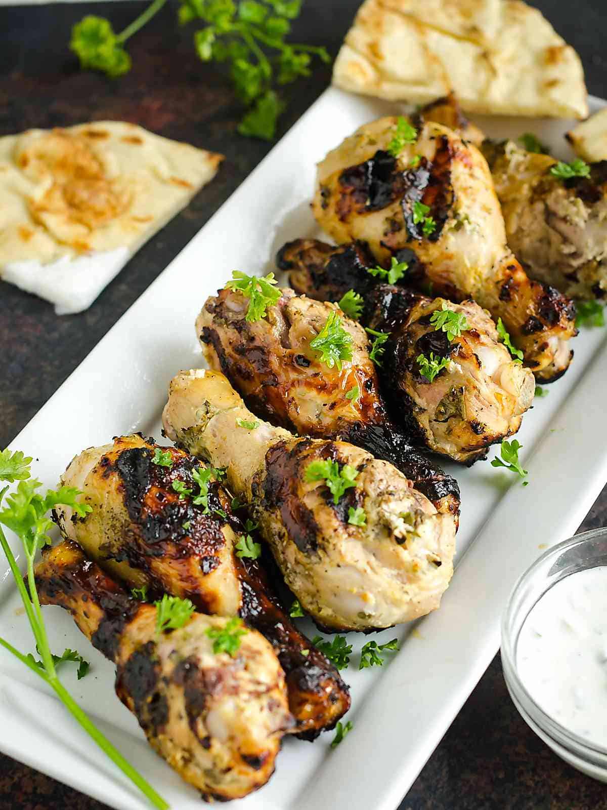 platter of grilled chicken drumsticks  that were marinated in a yogurt sauce, garnished with parsley.