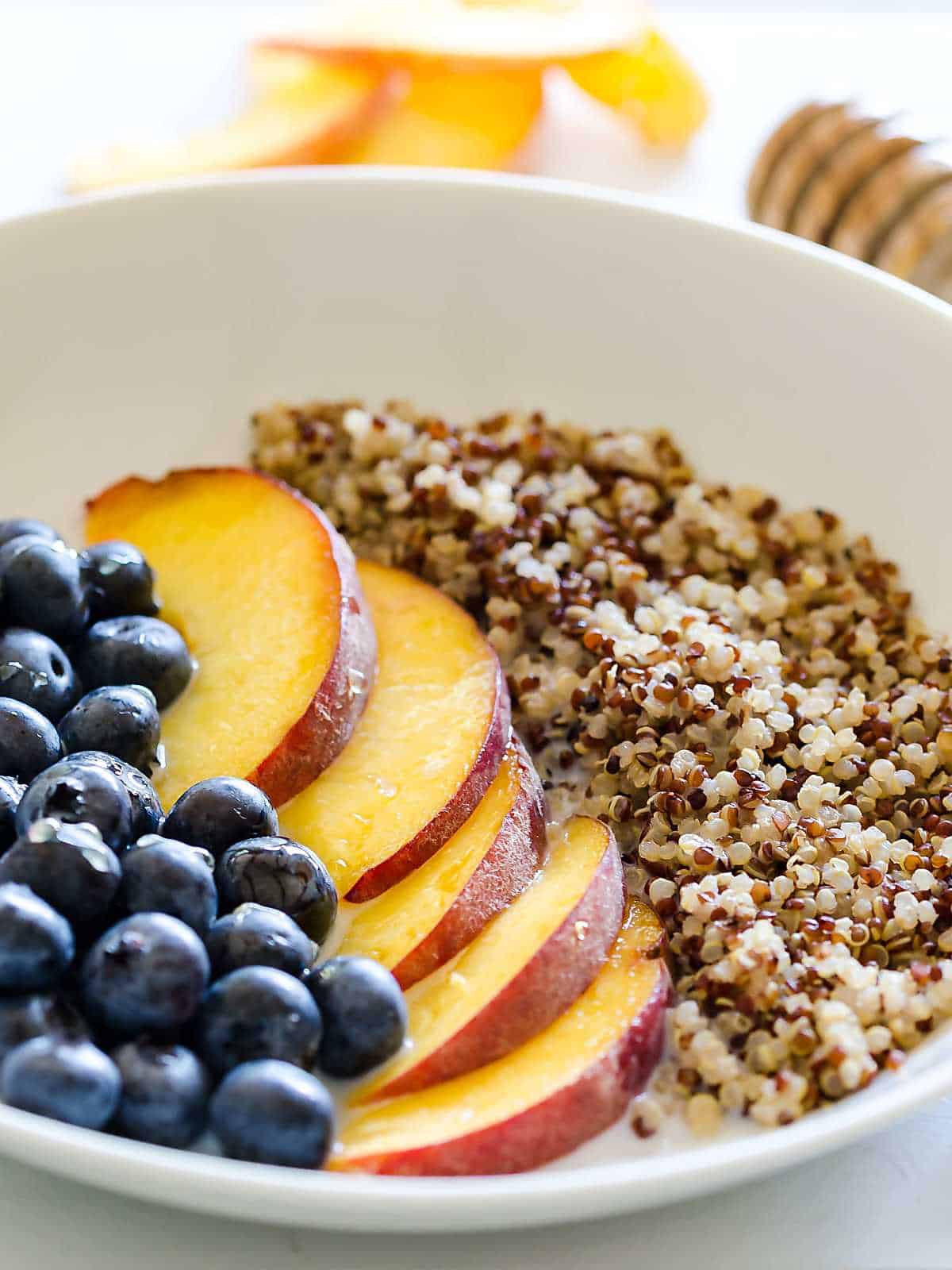 quinoa blueberries and peaches in a shallow white bowl, a row of each.