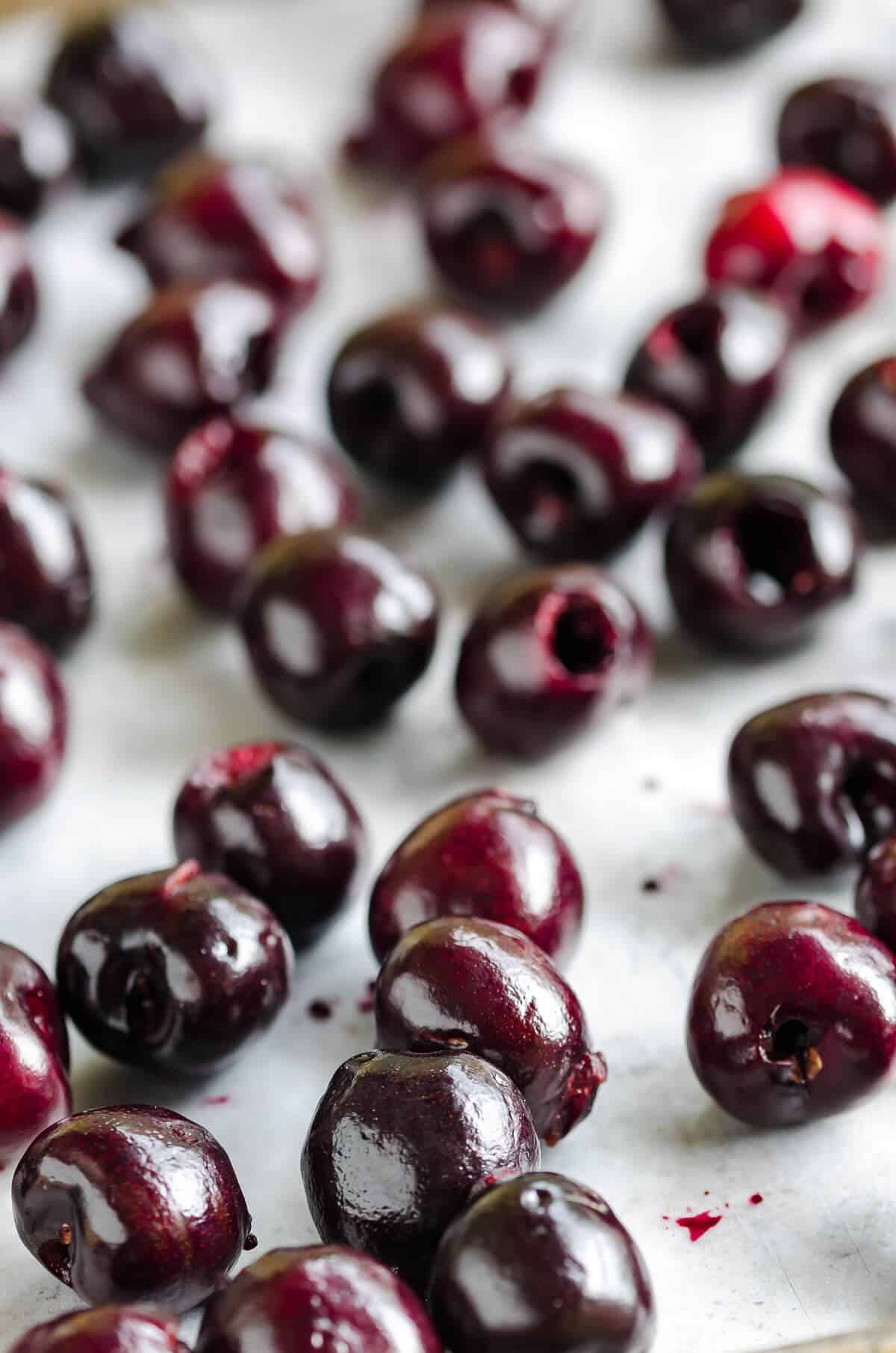 deep red fresh pitted cherries spread out on a sheet pan for freezing cherries