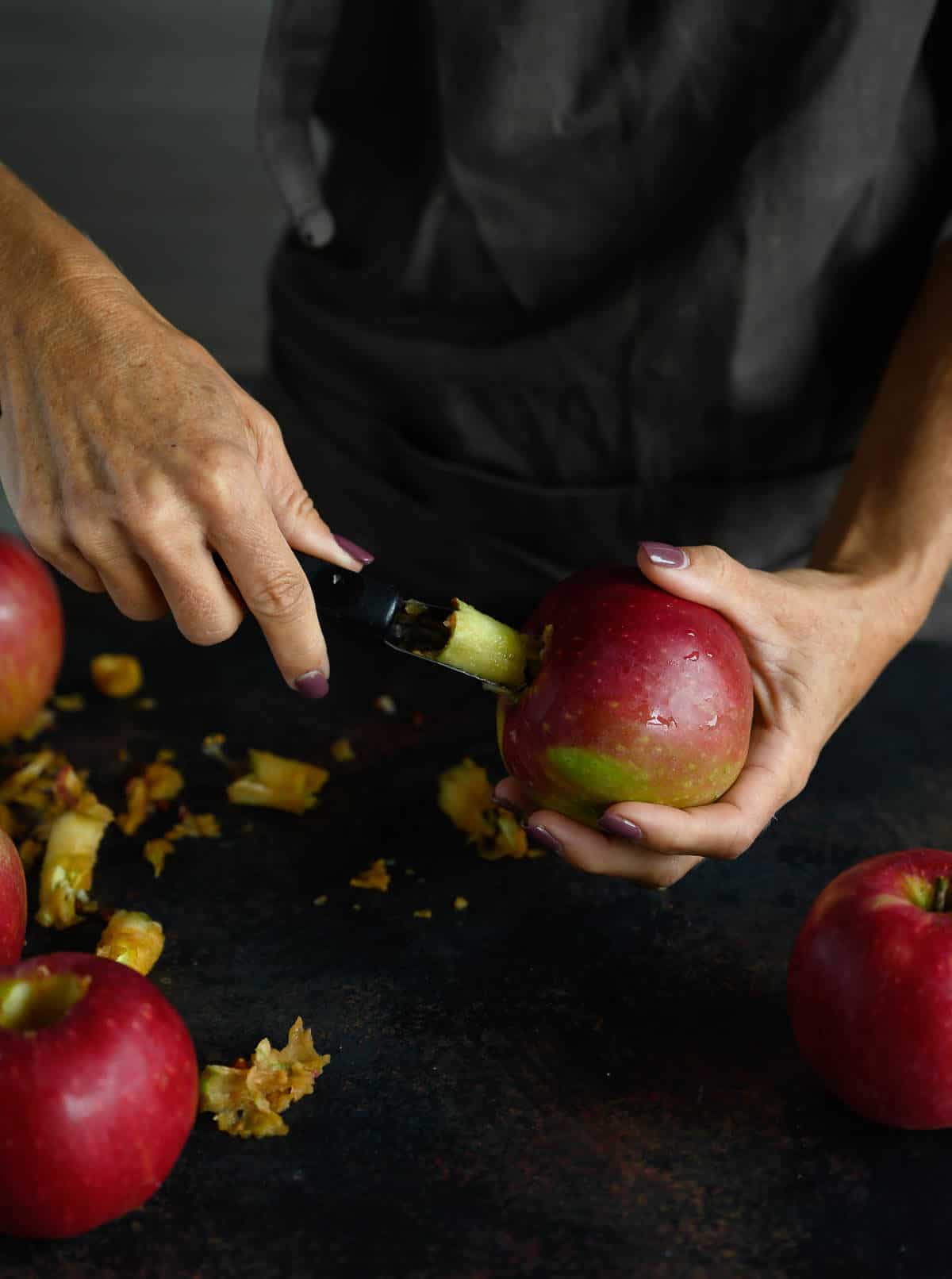 woman using an apple corer to remove the core of a whole apple