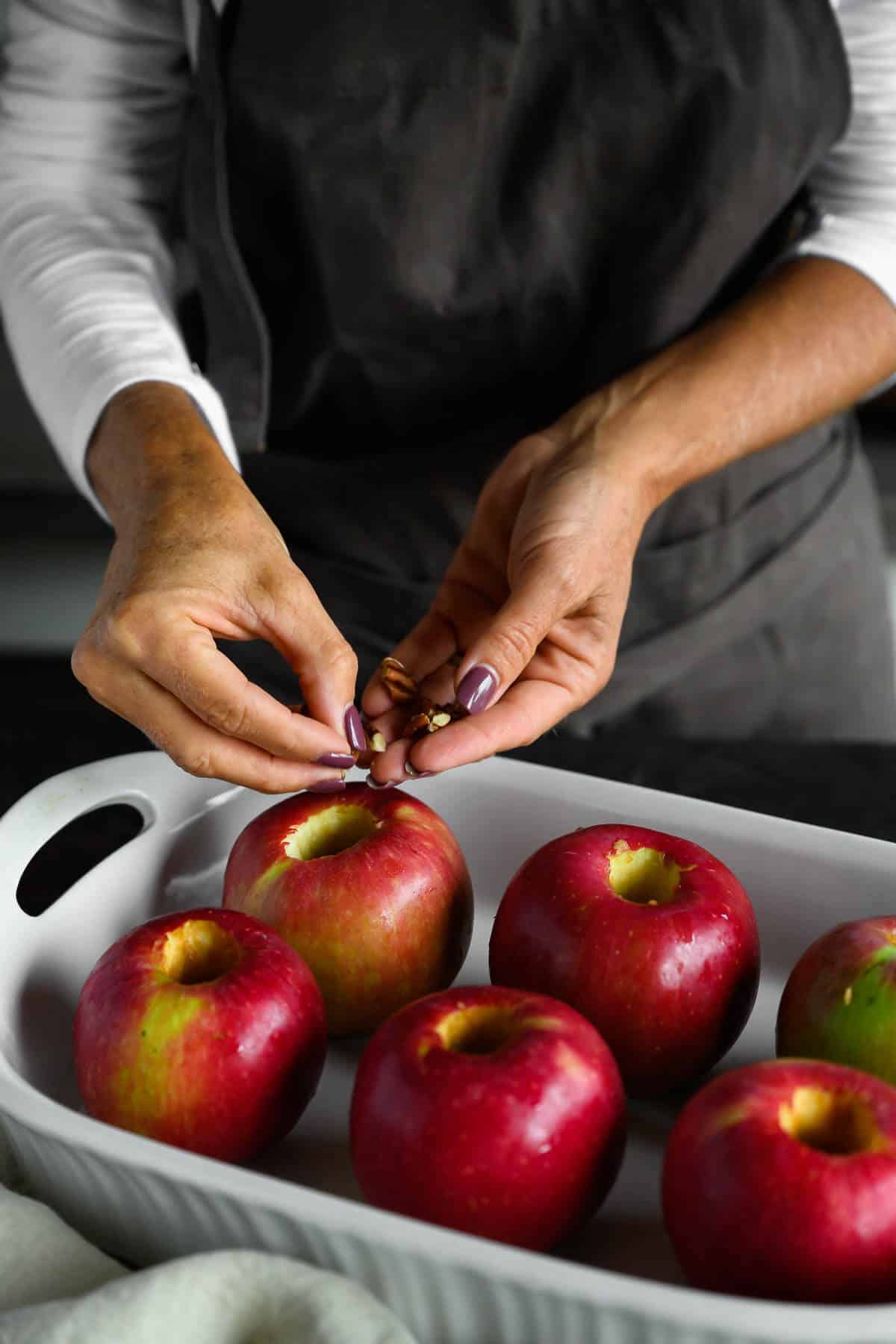 woman filling cored apples with chopped pecans