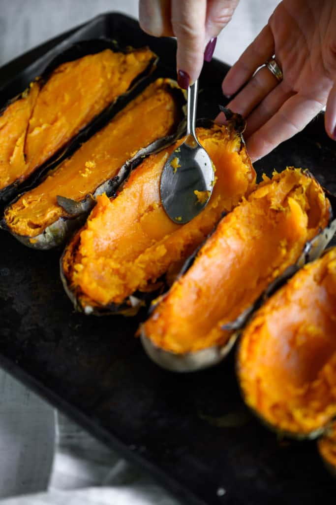 spoon makes a well in baked sweet potatoes