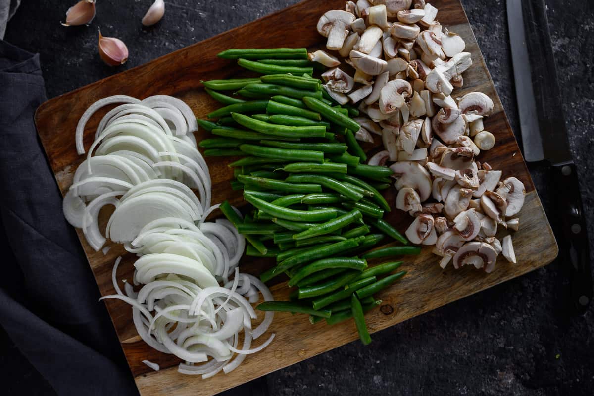 sliced onions, green beans, mushroom slices on a cutting board