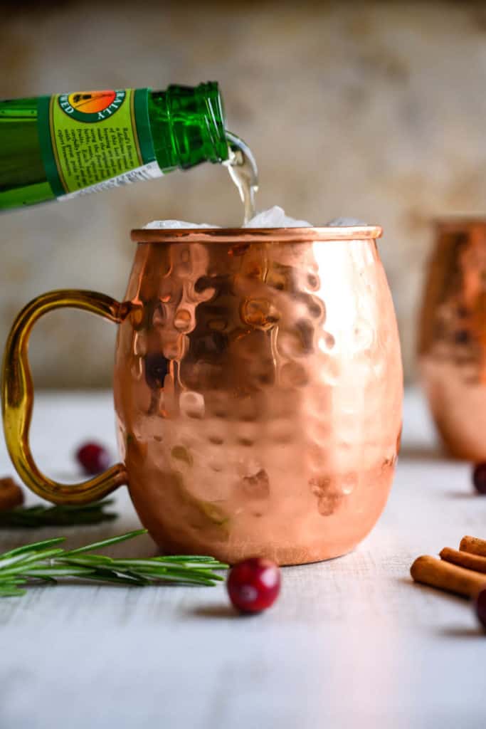 ginger beer being poured into a copper mug over crushed ice