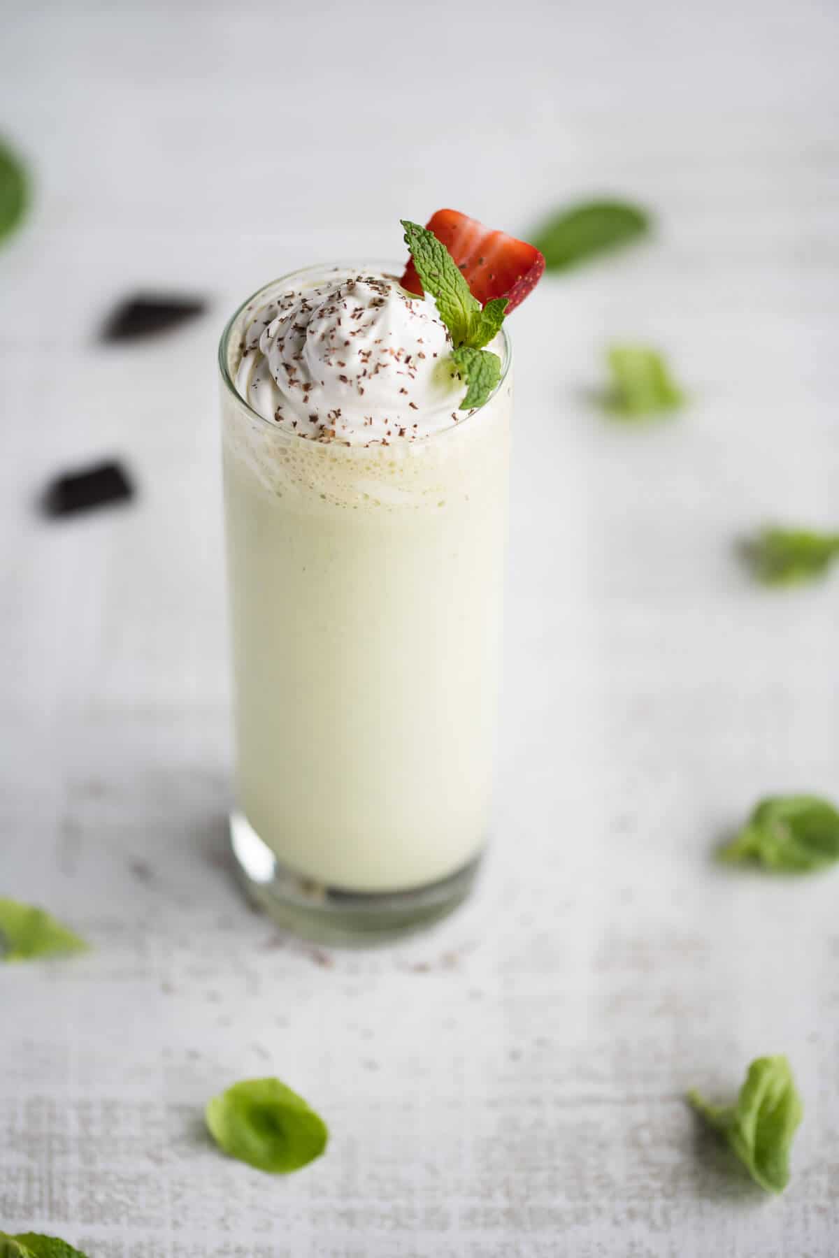 shamrock shake in a tall glass with whipped cream and fresh mint