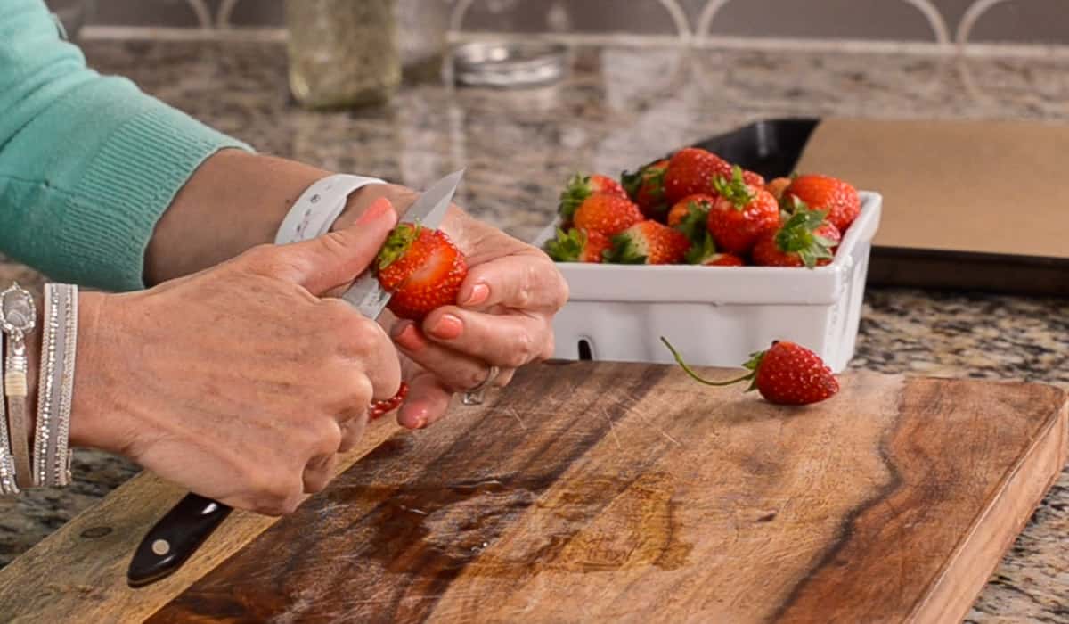 slicing strawberry stems off