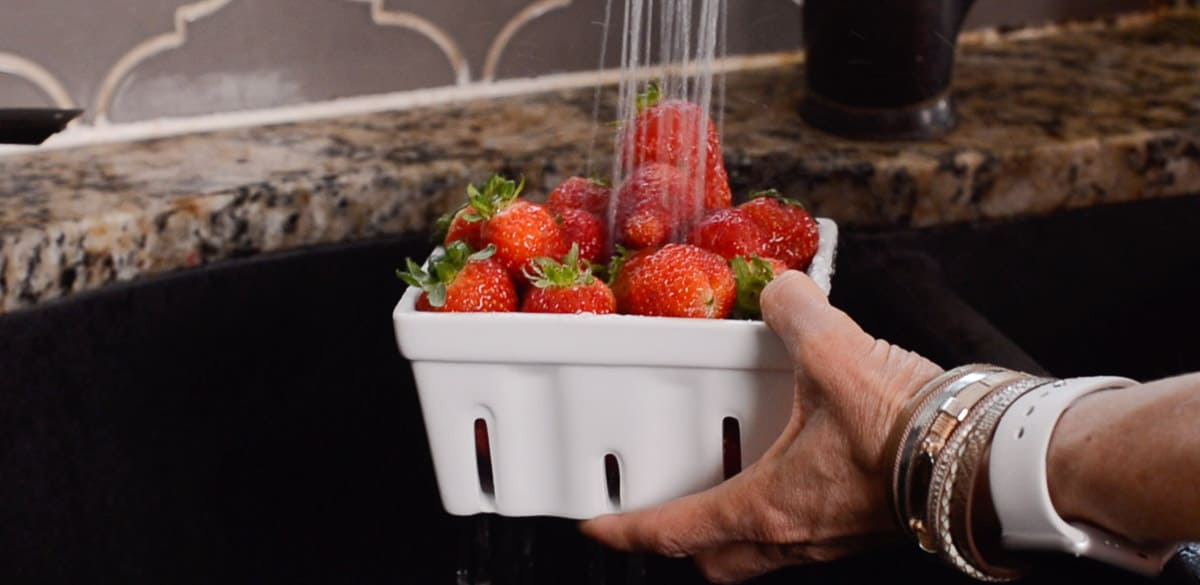 quart of fresh strawberries under running water