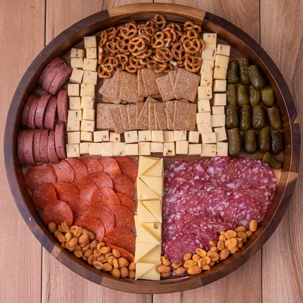 round charcuterie board where the meat, cheese, crackers and other elements represent a football field goal post