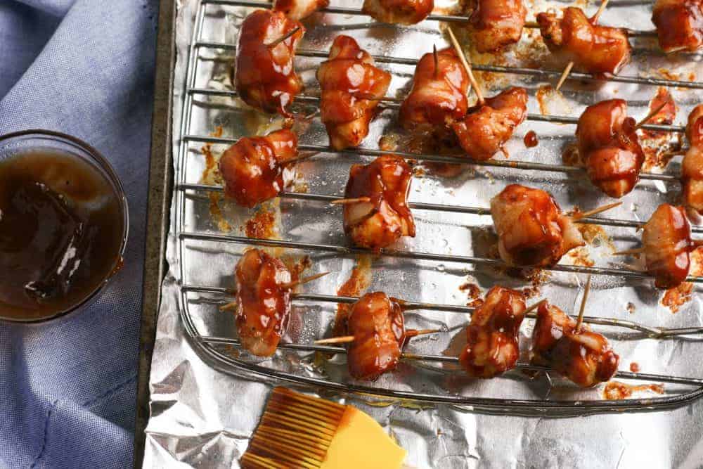 pieces of chicken wrapped in bacon and brushed in bbq sauce on a rack.