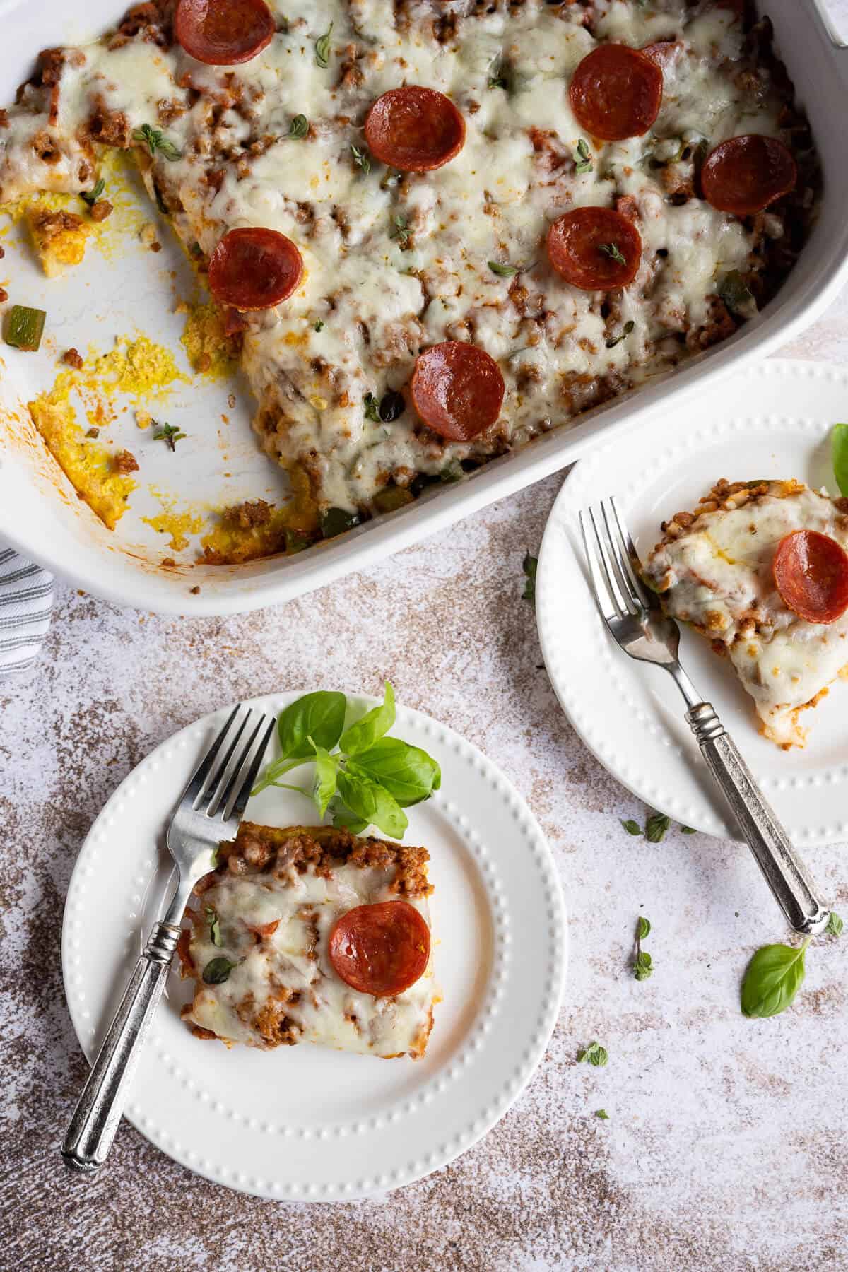 two plates with pieces of low carb pizza casserole garnished with fresh basil