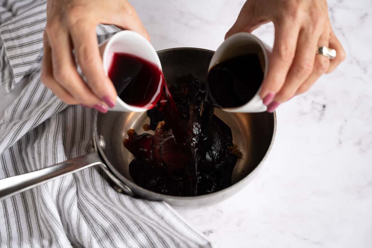 balsamic vinegar and pomegranate juice being poured in a pan over brown sugar