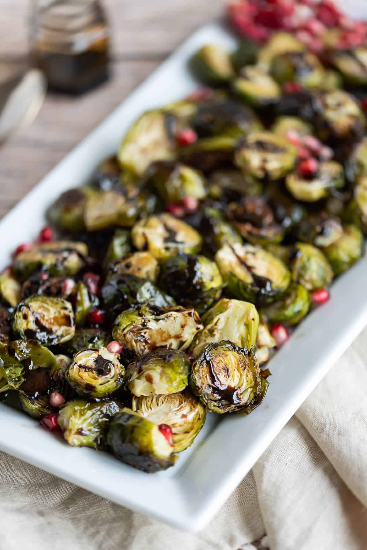Platter of roasted brussels sprouts drizzled with balsamic reduction.