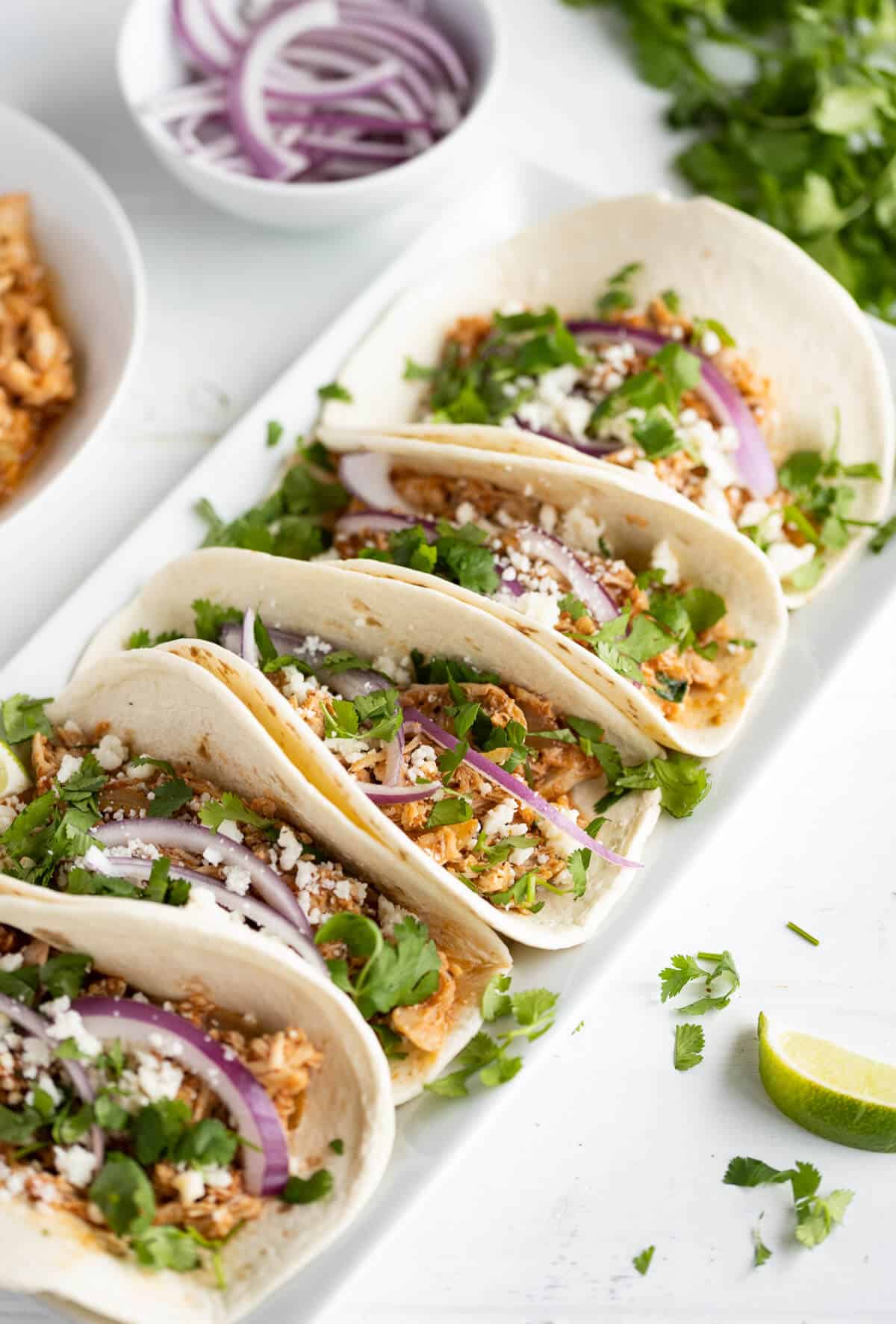 platter of soft tacos with chicken tinga, red onion, cheese, and cilantro