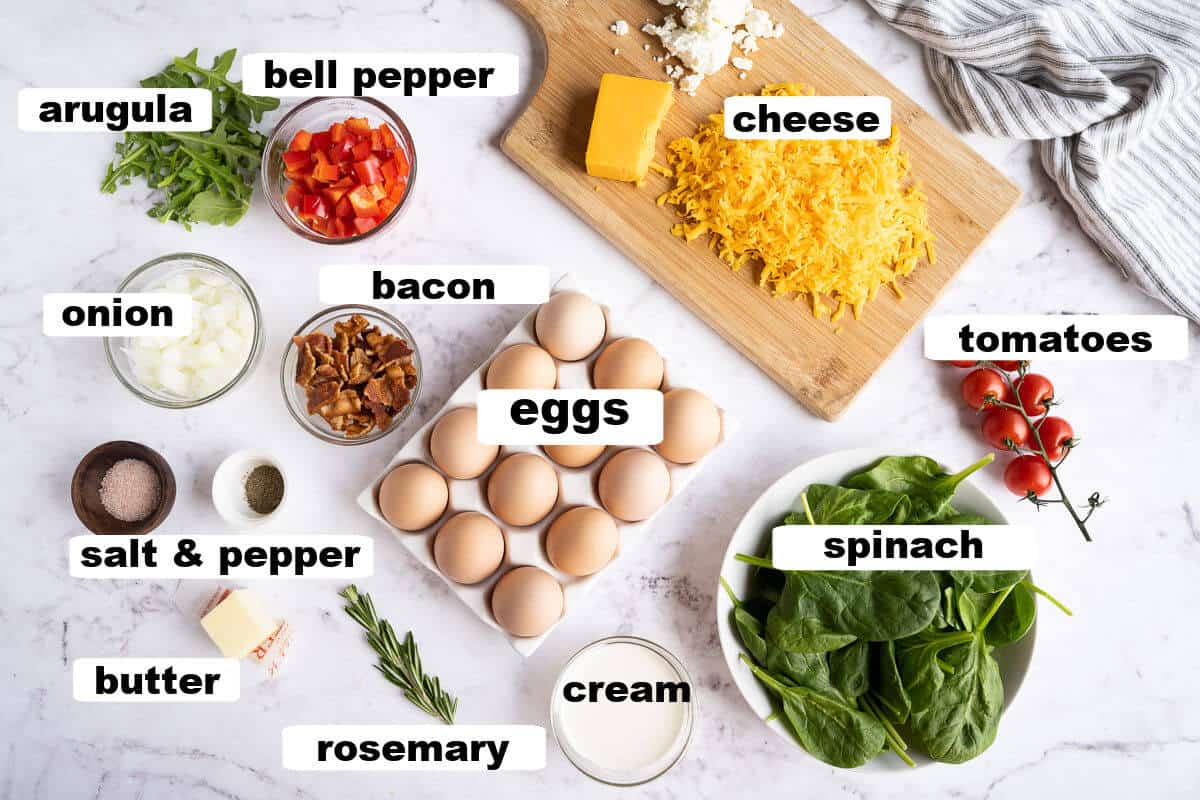ingredients for a frittata: eggs, cream, bacon, onion, bell pepper, salt, pepper, butter, spinach, tomatoes, cheese, rosemary, arugula