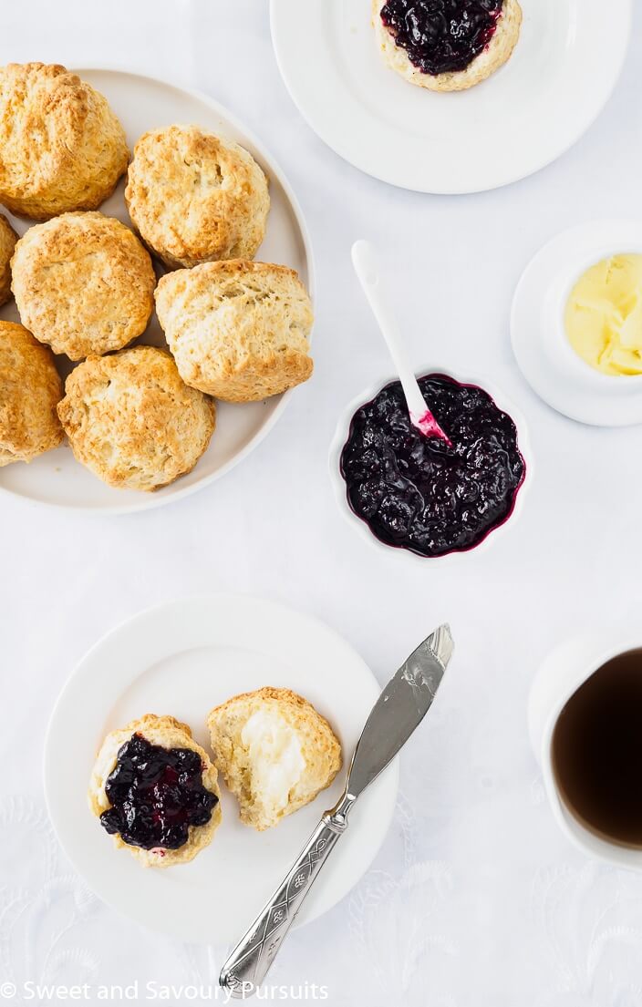 a plate full of round scones along side a plate with a single Irish scone topped with butter and jam