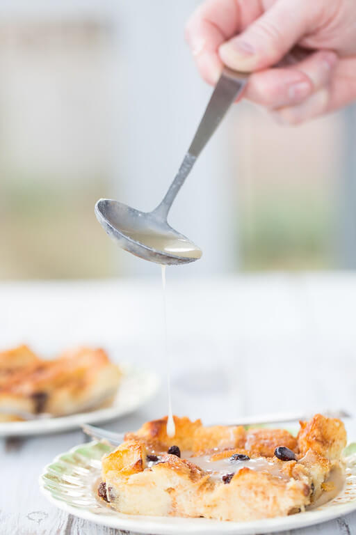 spoon pouring sauce over a piece Irish bread pudding