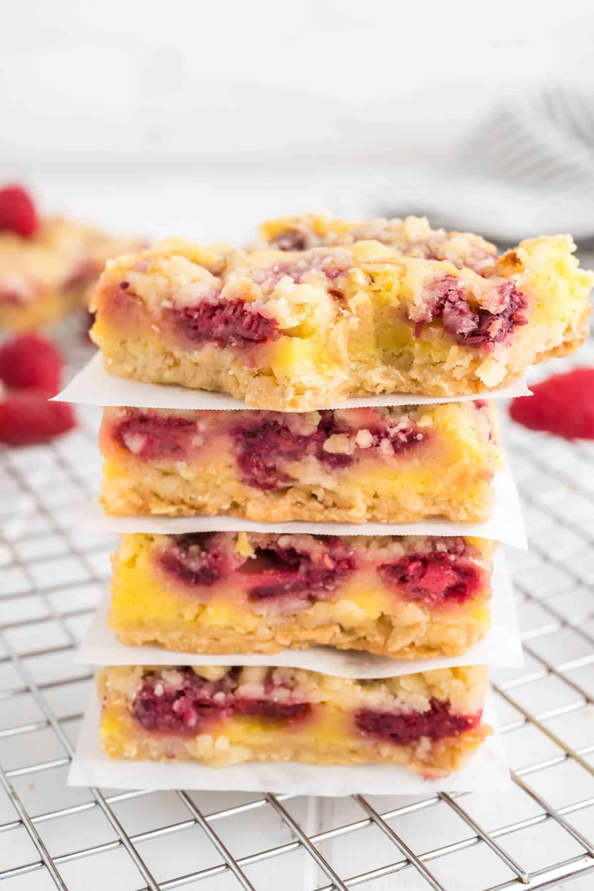 4 stacked raspberry bars with sheets of wax paper between them.