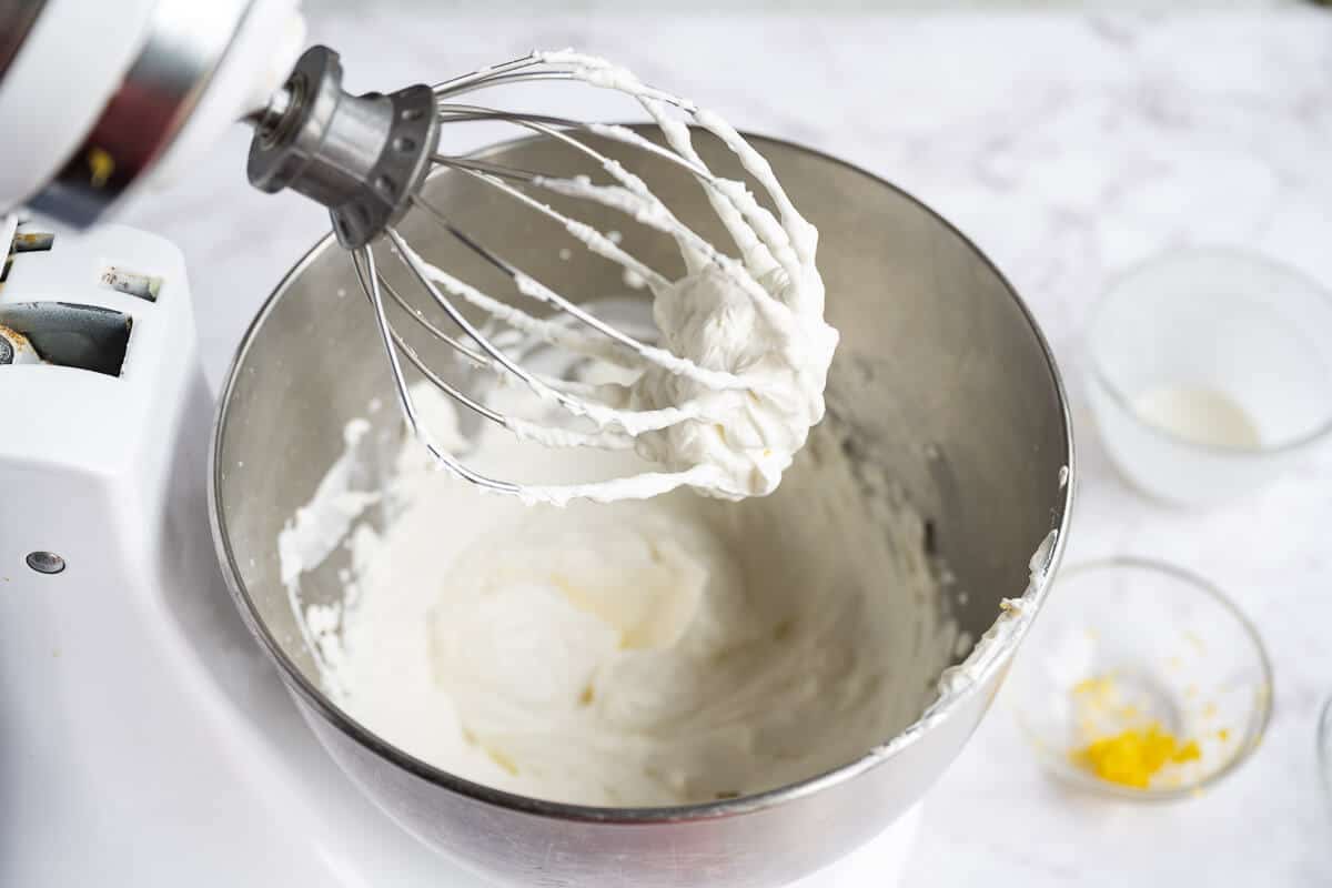 stand mixer wire whip with whipped cream on it.
