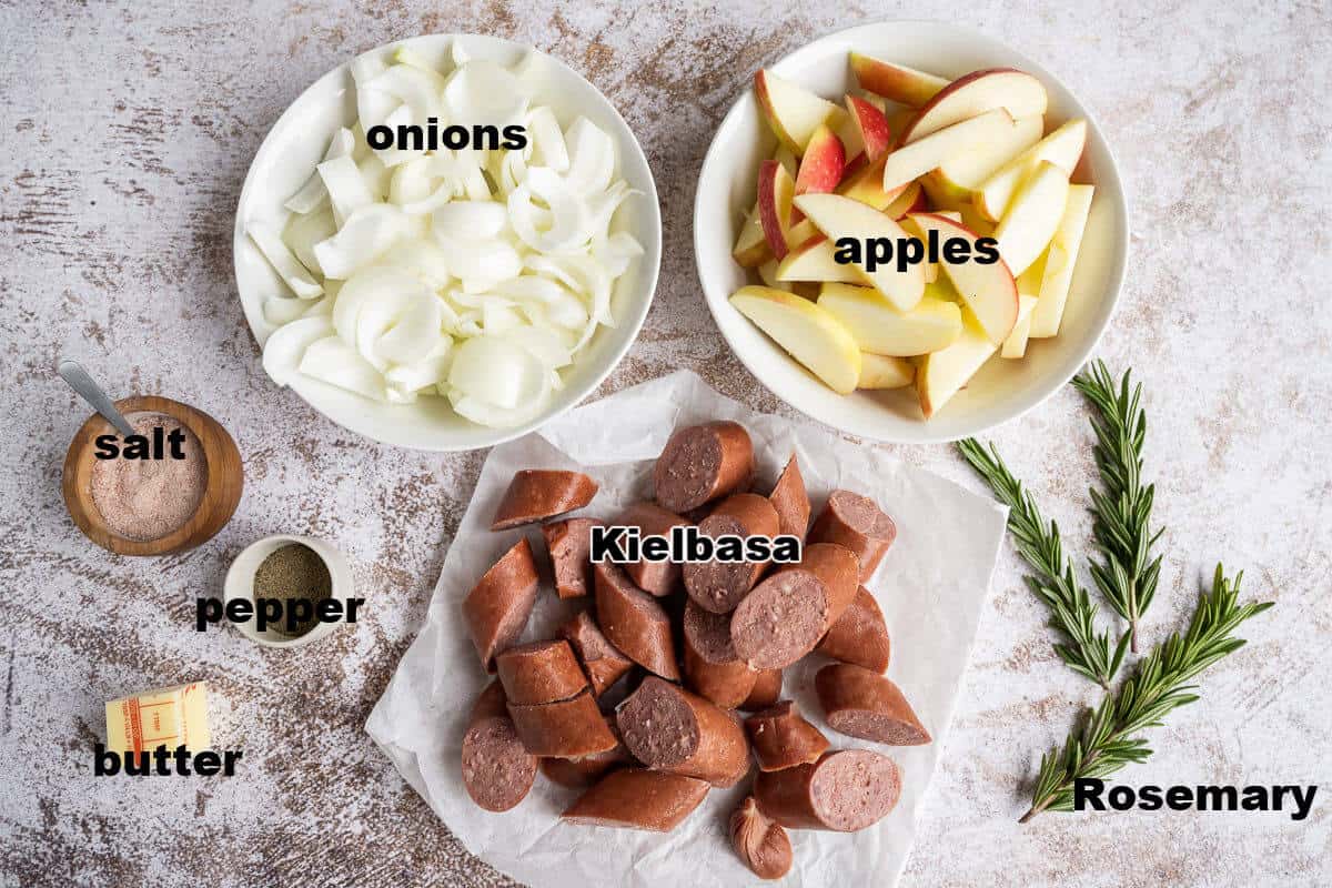 Ingredients for Kielbasa skillet dinner: onions, apples, kielbasa, salt, pepper, butter, and fresh rosemary.