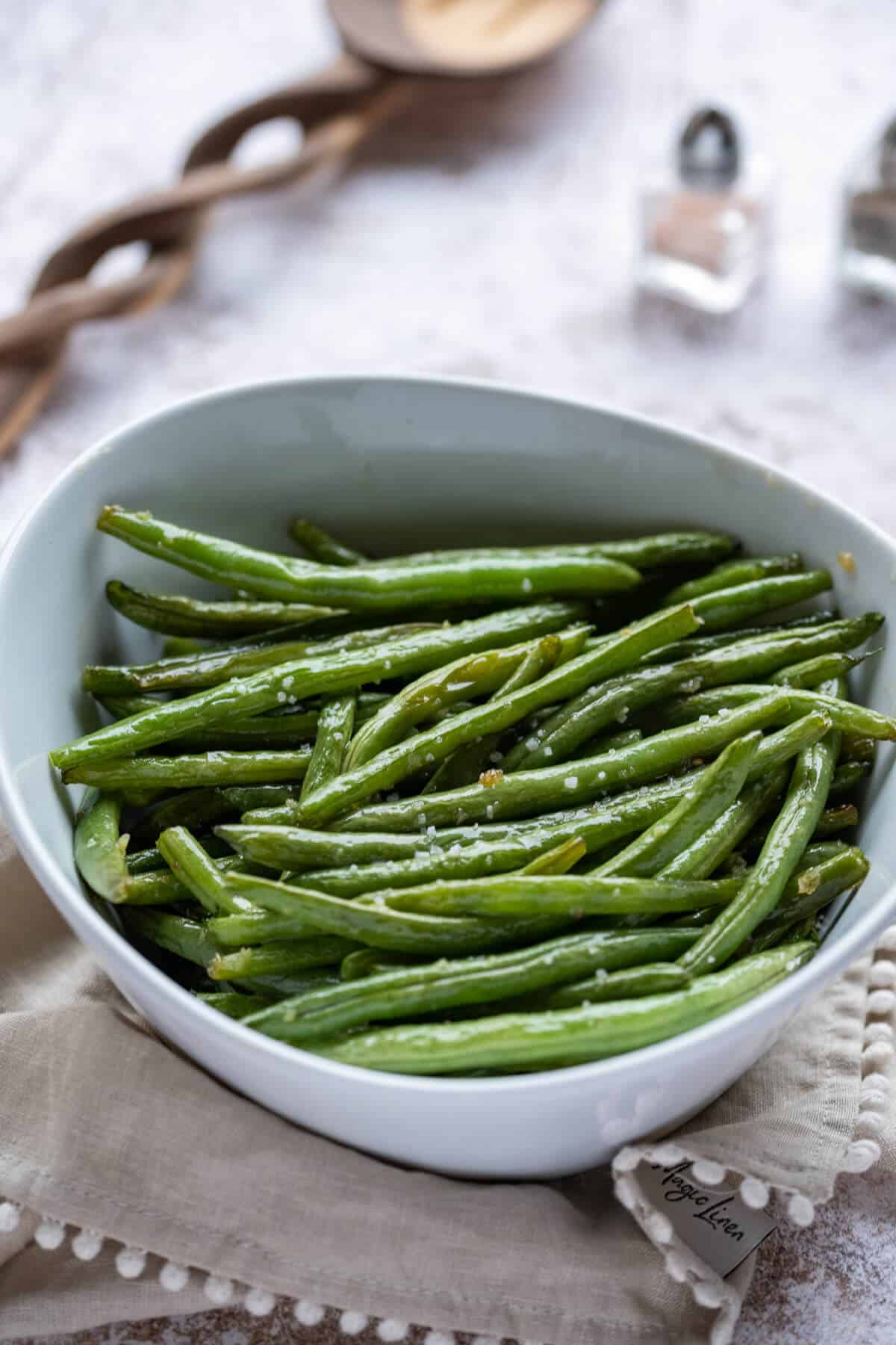 Garlic Butter Green Beans seasoned with coarse salt, in a white serving bowl.