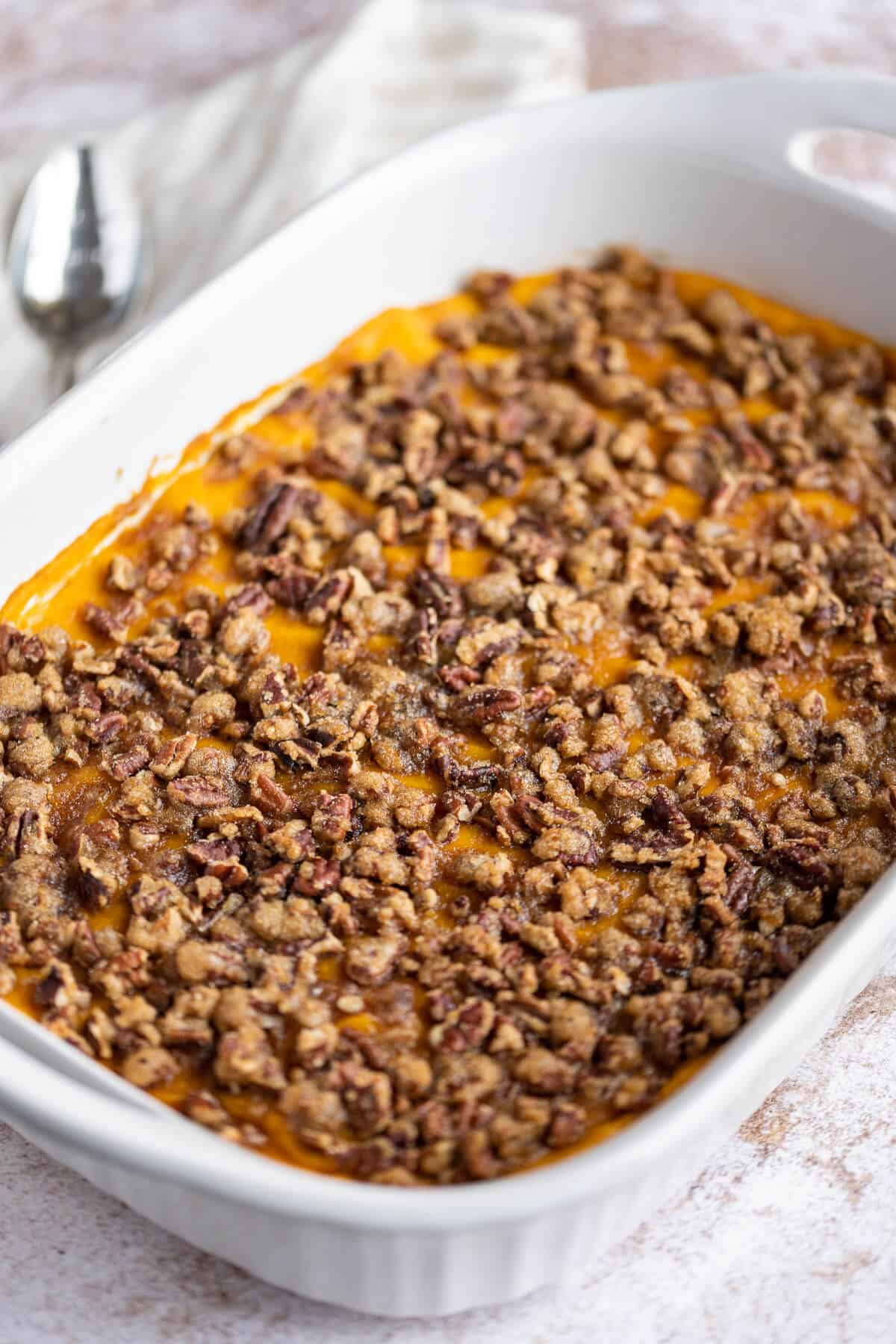 Sweet Potato Casserole with Praline topping in a white dish.