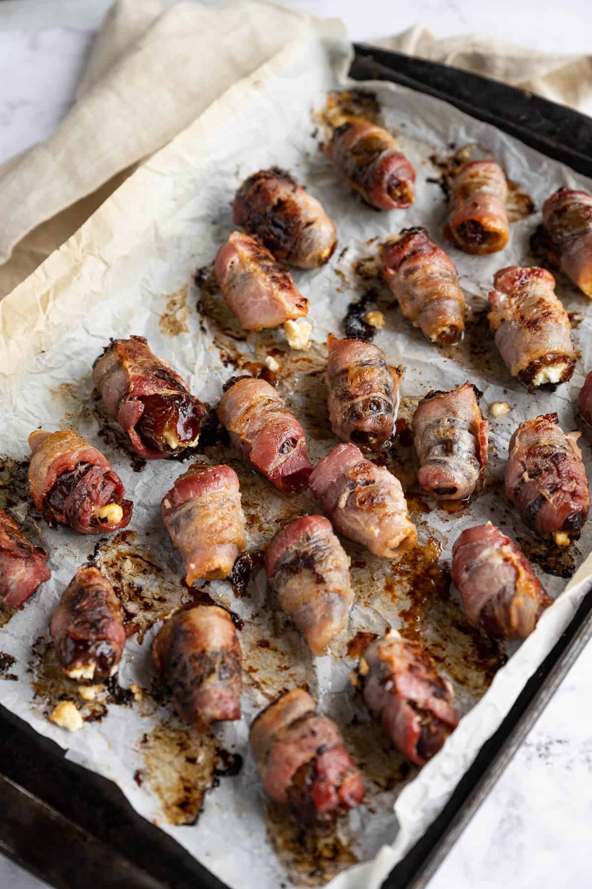 Baked bacon wrapped dates on a sheet pan.