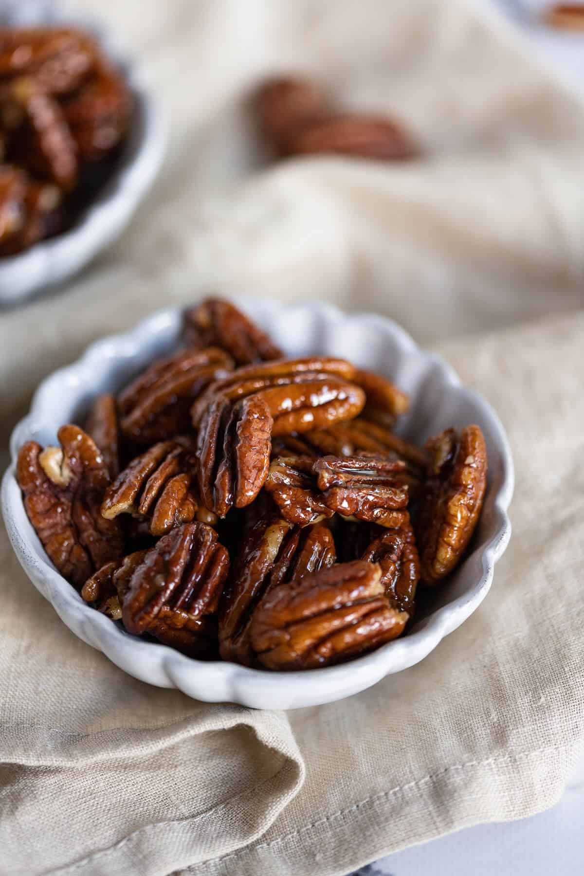 Caramelized pecan halves in a white bowl.