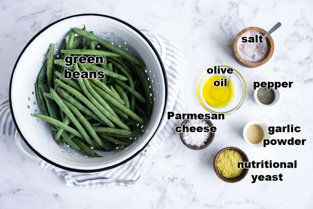Ingredients to make air fried green beans: fresh green beans, olive oil, salt, pepper, garlic powder, parmesan cheese and nutritional yeast.