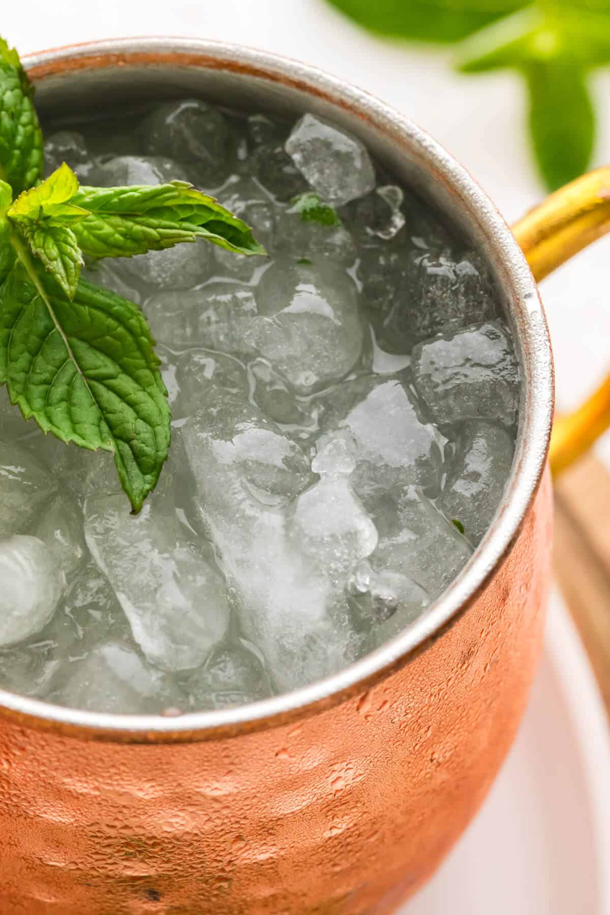Close up top down view of a Moscow mule in a copper mug with crushed ice and fresh mint.