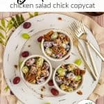 3 bowls of Chicken Salad Chick Grape Salad on. a round white platter with a few grapes scattered about. Large bowl of grape salad, scoop of brown sugar and a scoop of pecans are off to the side. Text overlay says "Grape Salad"