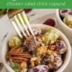 A fork reaching into a small bowl of grape salad garnished with brown sugar and a couple of whole pecans. Text overlay reads: "Grape Salad chicken salad chick copycat"