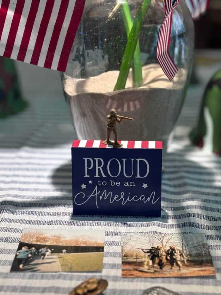 Proud to be and American wooden sign with photos in front.