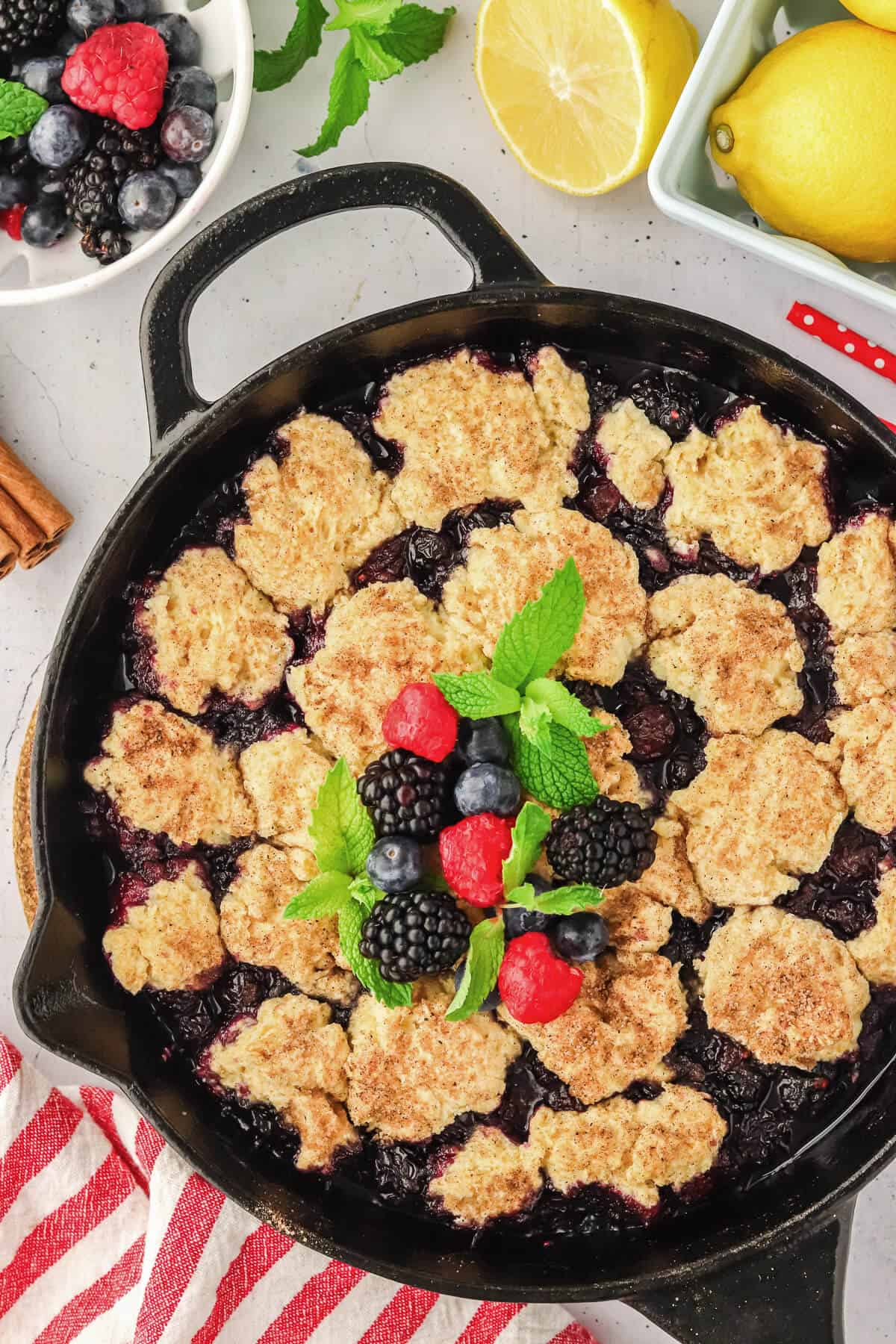 Mixed Berry Cobbler in a cast iron skillet. The cobbler is garnished with fresh berries and mint leaves.