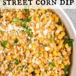 Close up image of Mexican Street Corn Dip in a round platter garnished with cilantro and cotija cheese crumbles. Text overlay reads: Mexican Street Corn Dip.