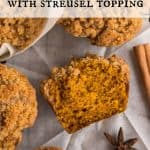 Overhead view of Pumpkin streusel muffins on a baking rack lined with parchment paper. One muffin is cut in half laying on its side. Cinnamon stick and star anise are off to the side as a garnish. Text overlay reads: Pumpkin Muffins With Streusel Topping.